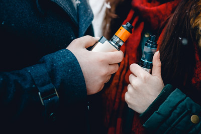 Two People Holding Vapes