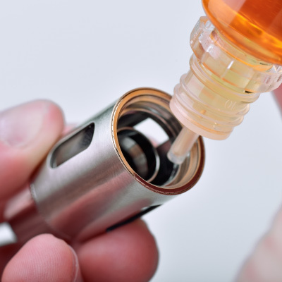 Man Priming a Coil Before Refilling Vape Tank