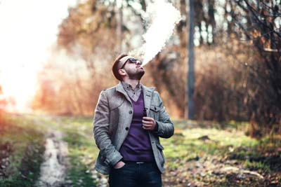 Man with beard vaping outdoor e cigarette