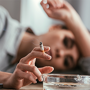 Woman Using Ash Tray for a Cigarette at Her Desk