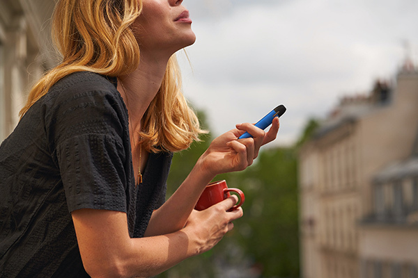 Woman Vaping Outdoors on a Balcony